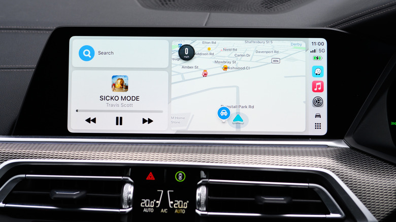 Apple CarPlay in use inside a car, the left side showing Apple Music playback, with the right side showing Apple Maps navigation.