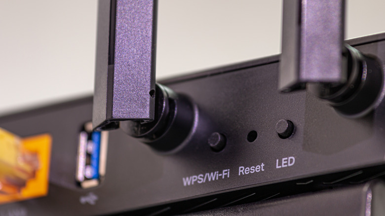 The WPS button on the back of a router, alongside the reset pinhole and LED control switch.