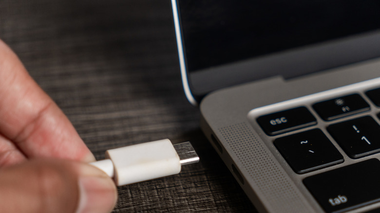 A person plugging a USB-C cable into their MacBook.