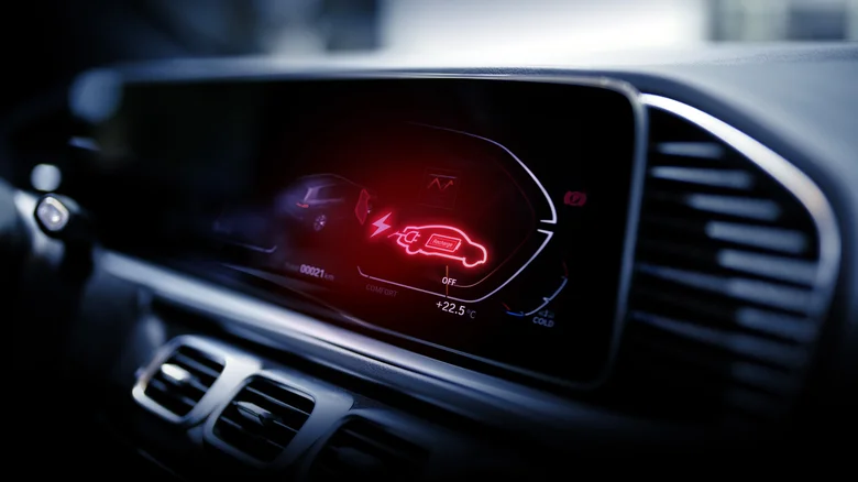 Electric vehicle dashboard displaying a red battery recharge warning with an illuminated EV icon.