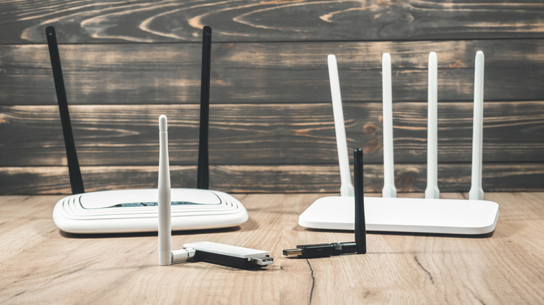 A set of Wi-Fi routers and USB Wi-Fi adapters on a wooden table.