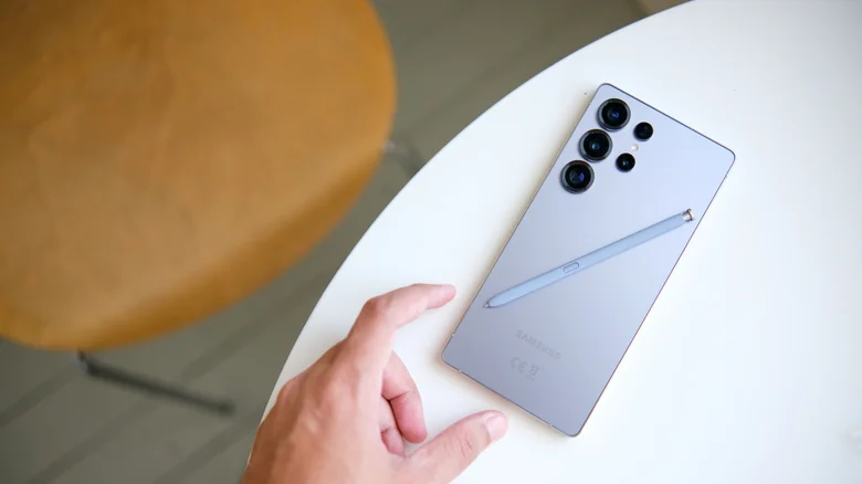 Samsung phone sitting face down on desk, stylus laying on top of it.