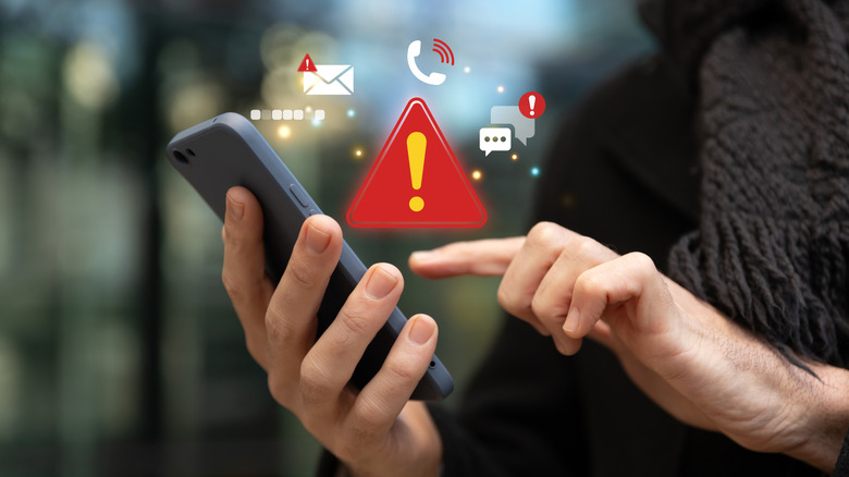 A woman using a smart phone presses on the screen, above which are a series of red alert graphics.