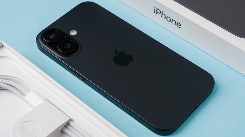 An iPhone face-down on a blue table, next to the two parts of its box.