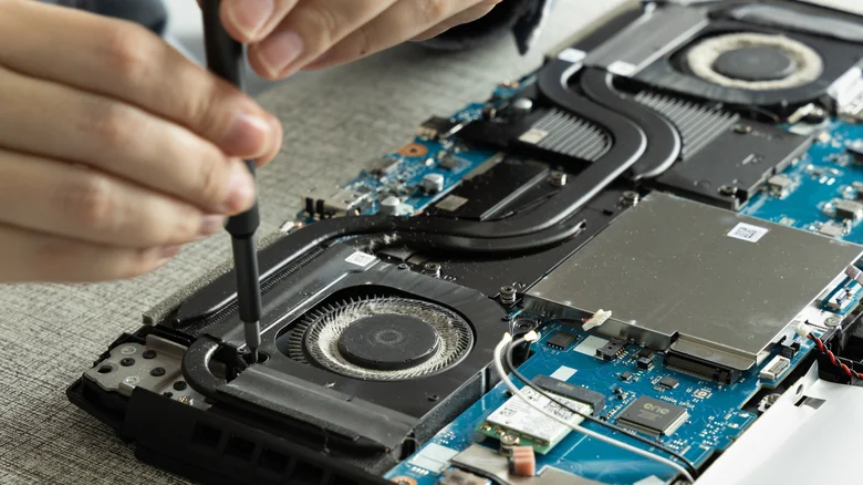 An open laptop with two cooling fans, heat pipes and the motherboard exposed.