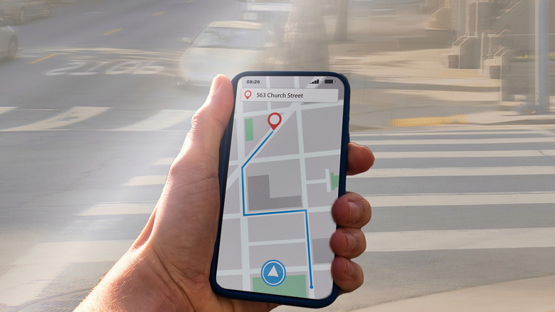 Hand holding a smartphone, viewing directions to a city destination.