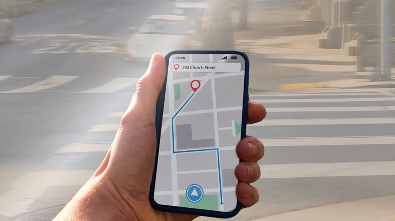 Hand holding a smartphone, viewing directions to a city destination.
