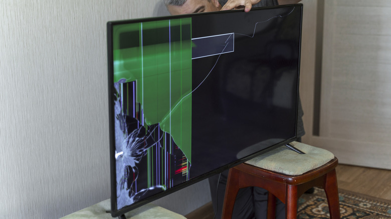 A heavily damaged TV with a smashed panel.