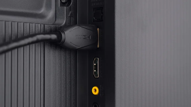 An HDMI cable plugged into the back of a TV, alongside various other ports.