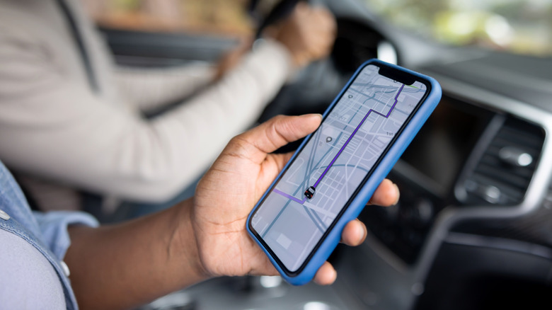 Person using navigation app on iPhone as passenger in car