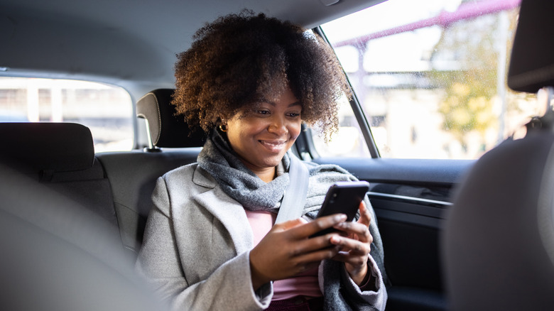 A passenger looking at her phone in the car.