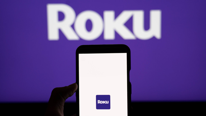 Roku app shown on phone with TV in background