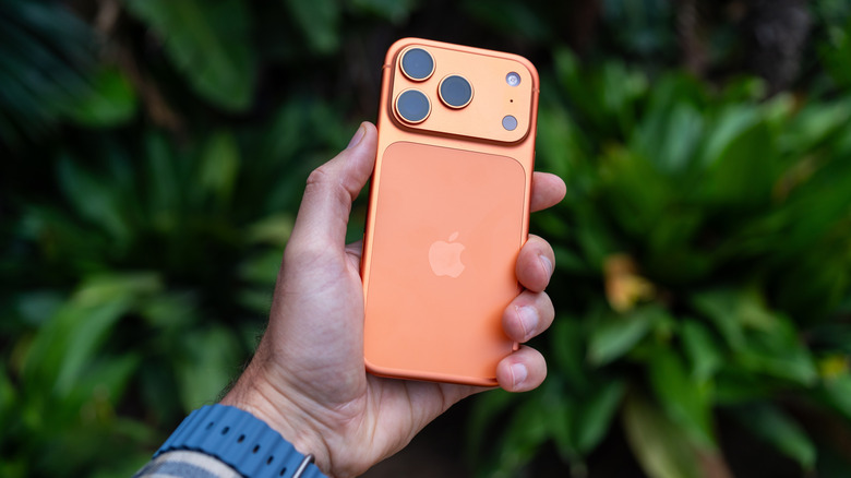 A hand holding an orange iPhone 17 Pro.