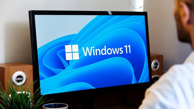 A man using a PC with the Windows 11 logo showing.