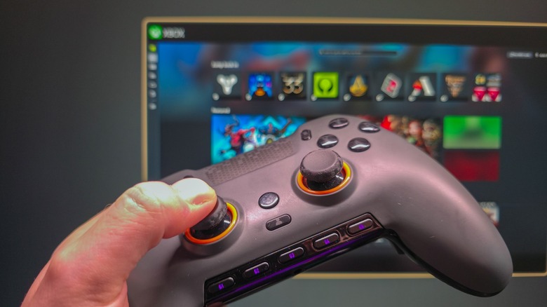 Scuf controller in a hand with Xbox mode on Windows in the background.