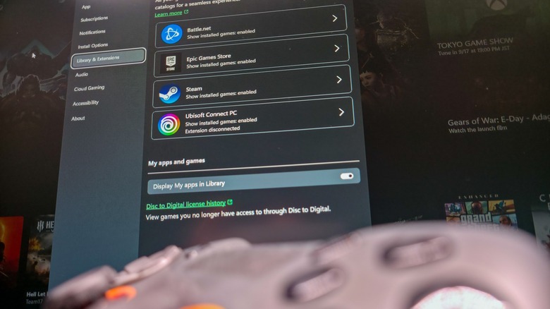 Scuf gamepad blurred in the foreground with Xbox app library integrations in background.