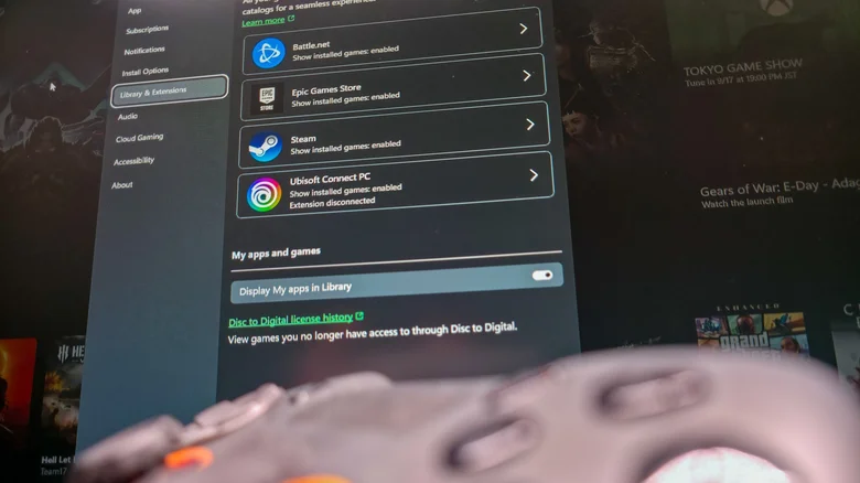 Scuf gamepad blurred in the foreground with Xbox app library integrations in background.