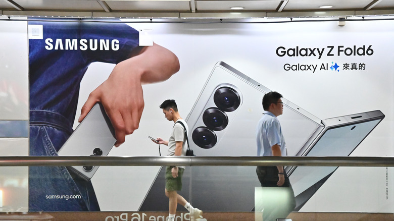 Two people walking past an advertisement for the Galaxy Z Fold6.