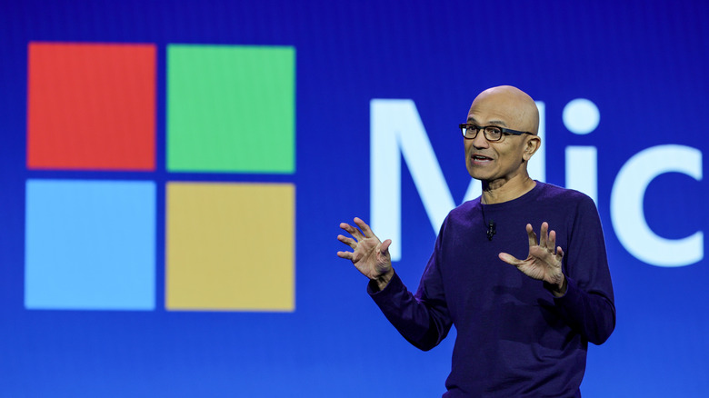 Satya Nadella presenting in front of a Microsoft logo.