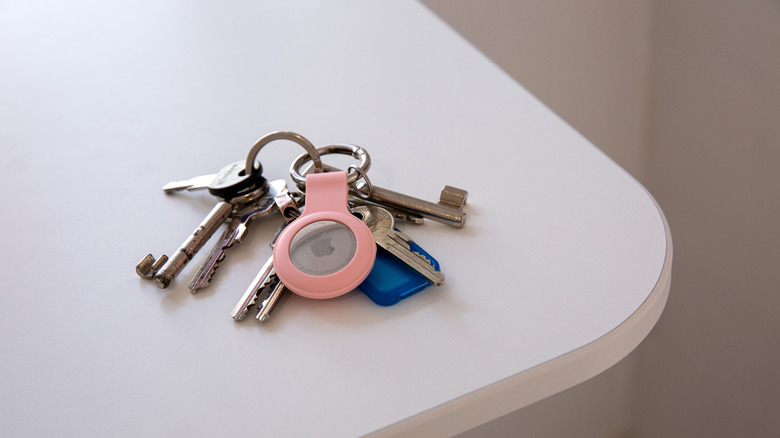 An AirTag in a pink case on a keyring.