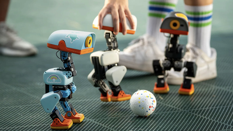 Microduck robots playing soccer on a floor