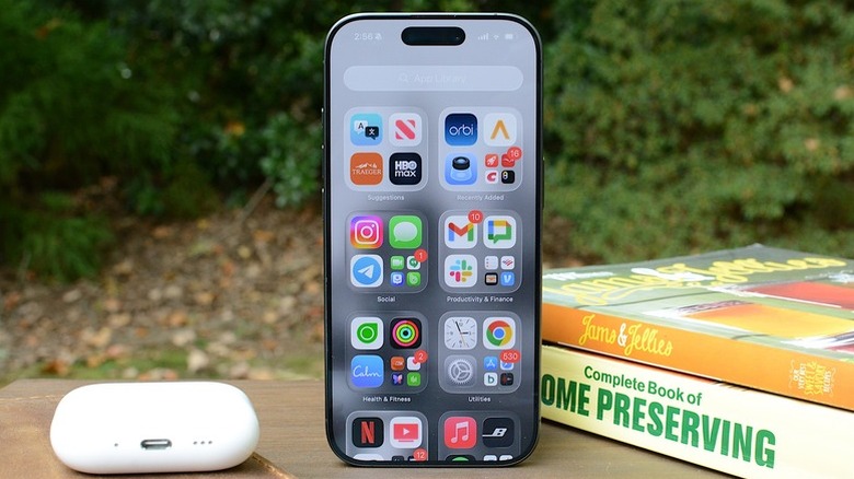 An iPhone 17 sits next to an AirPods Case and a couple of books.