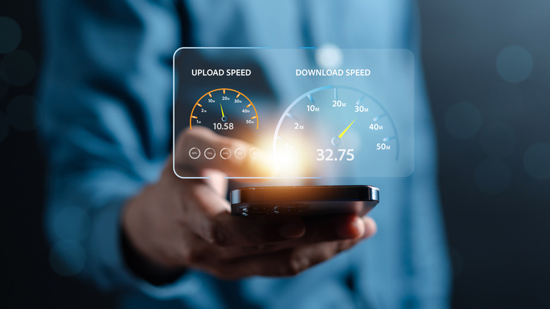 A person holding a phone with an holographic overlay showing upload and download speed gauges.