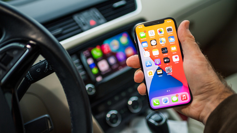 A hand holding an iPhone in the car