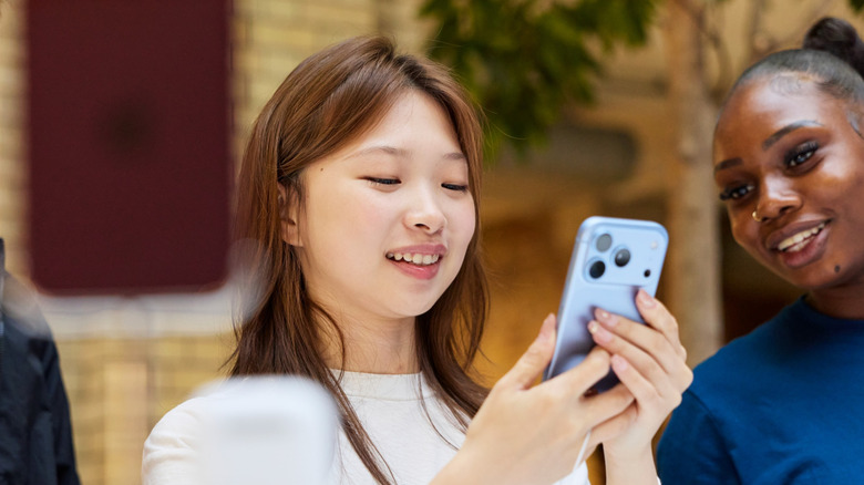 A woman in white holds an iPhone at an Apple Store in London.