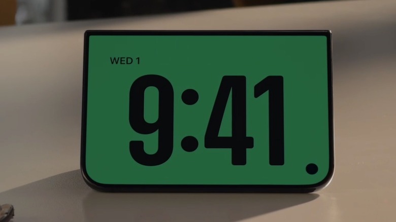 An iPhone Duo in kickstand mode shows the time.