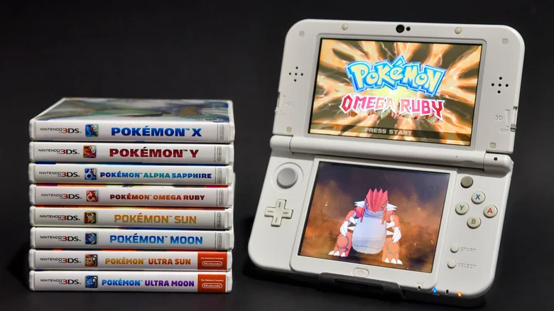 A stack of 3DS Pokémon games next to an open 3DS with Pokémon Omega Ruby open.