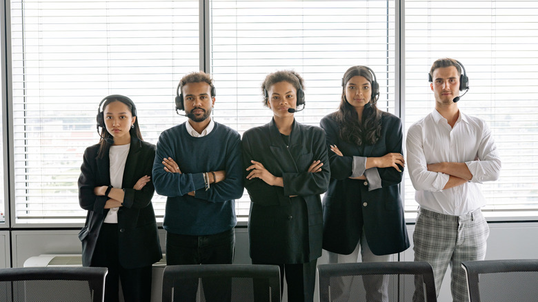 A group of office workers wearing headsets with their arms crossed