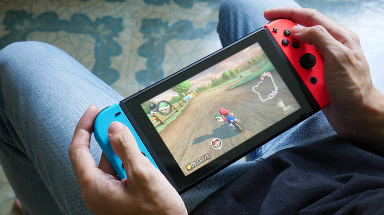 Person playing Mario Kart 8 Deluxe on a Nintendo Switch in handheld mode