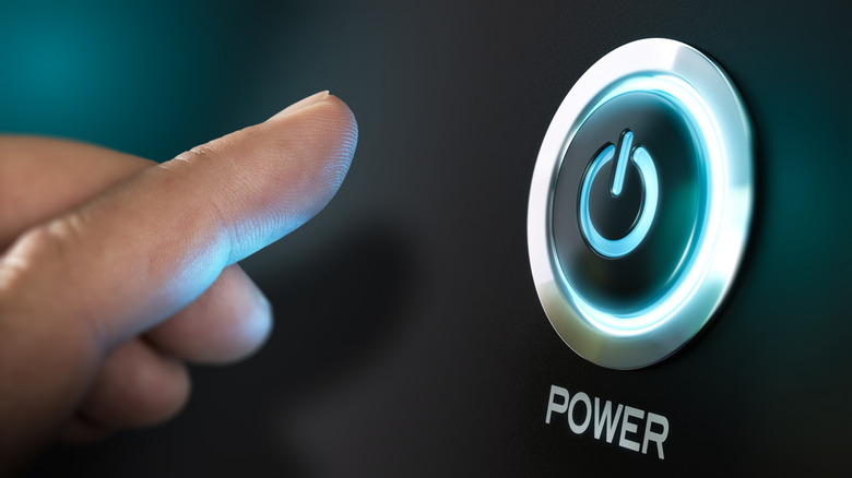 A finger about to press a power button.