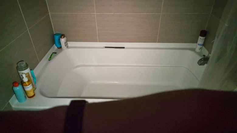 Using smartwatch flashlight to illuminate bathtub in dark bathroom.