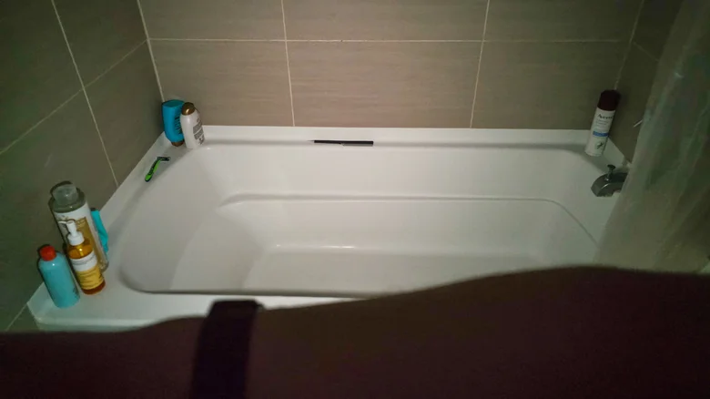 Using smartwatch flashlight to illuminate bathtub in dark bathroom.