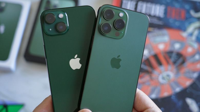 Green iPhone 13 and iPhone 13 Pro models in hand.