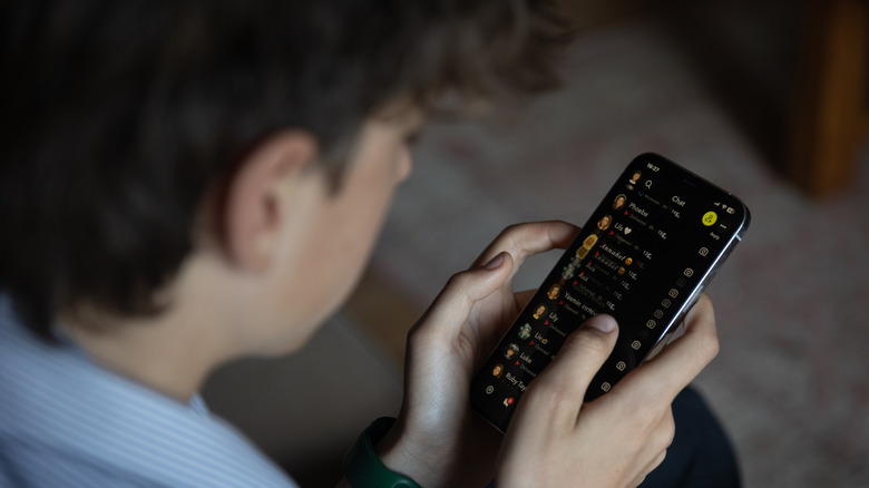 A boy looking at Snapchat on a phone.
