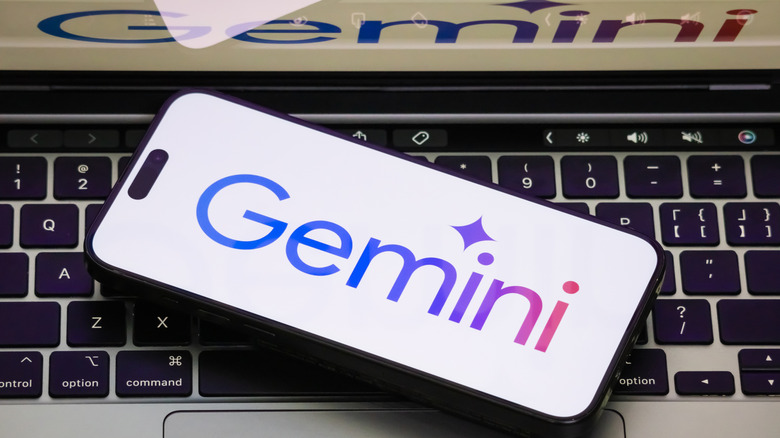 Google Gemini name on phone's display on top of laptop keyboard.