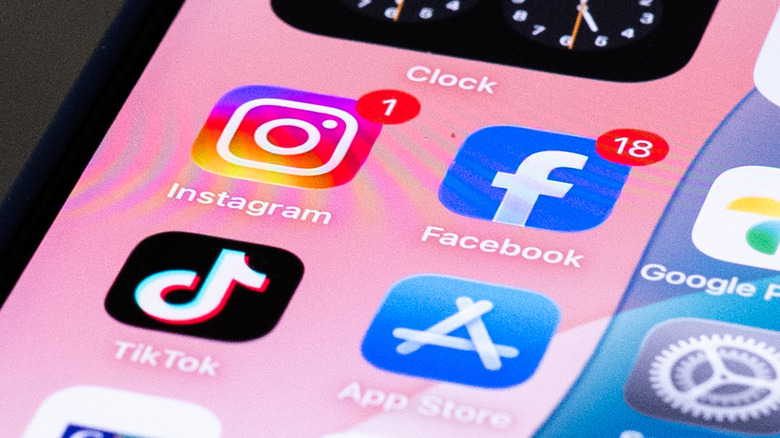 Instagram, Tiktok and Facebook icons are shown on the home screen of an iPhone against pink