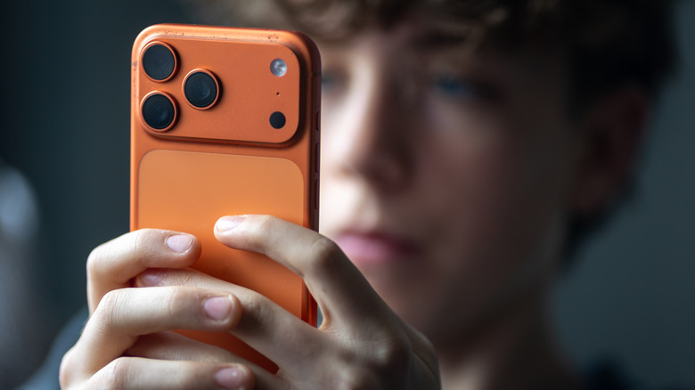 A teen looking at a smartphone.
