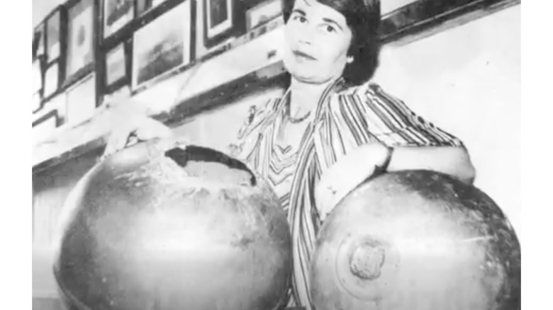 Black and white photo from the 1970s of a person posing with two space balls.