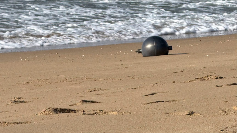A large metallic ball sitting on the beach