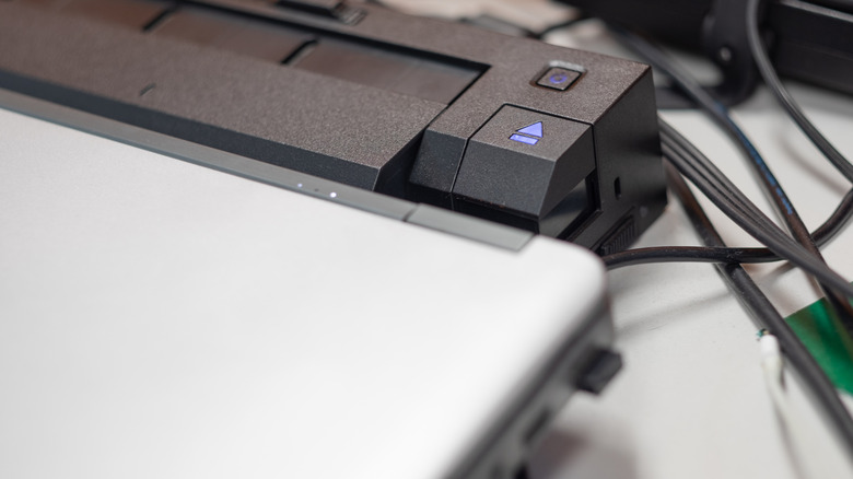 A docking station beside a laptop with several connected cables.