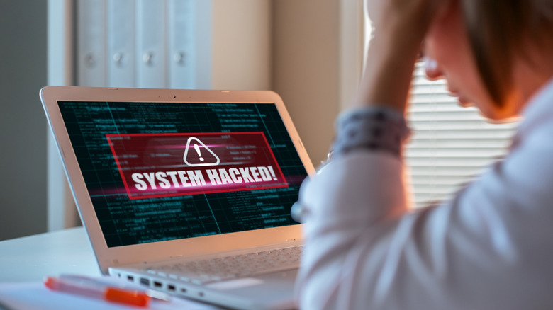 Upset woman discovering that her laptop has been hacked.