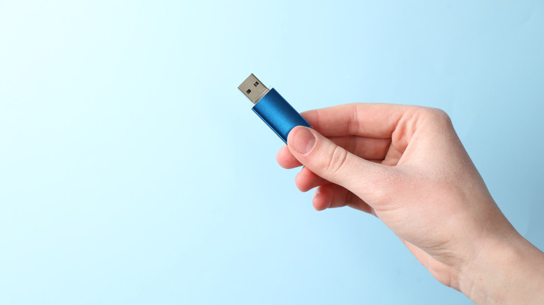 Hand holding USB thumb drive.