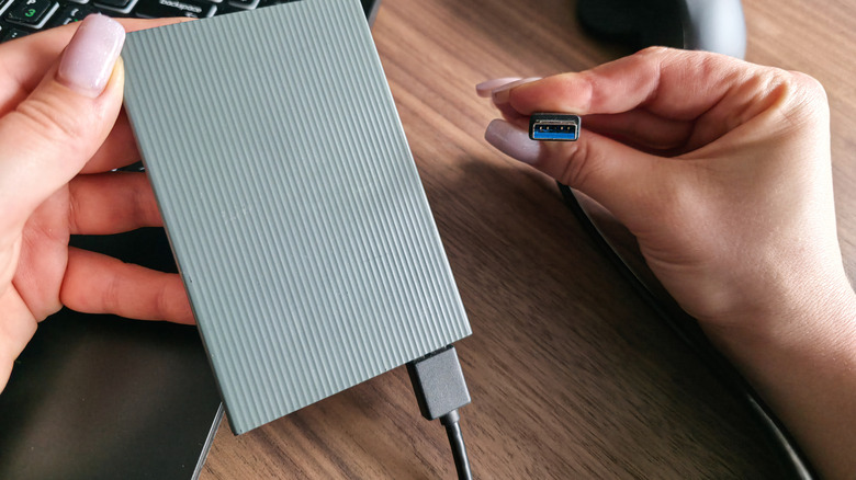 Woman preparing to connect a USB hard drive to a laptop.