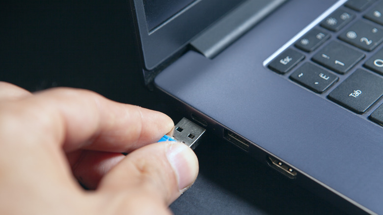 Hand plugging USB device into laptop