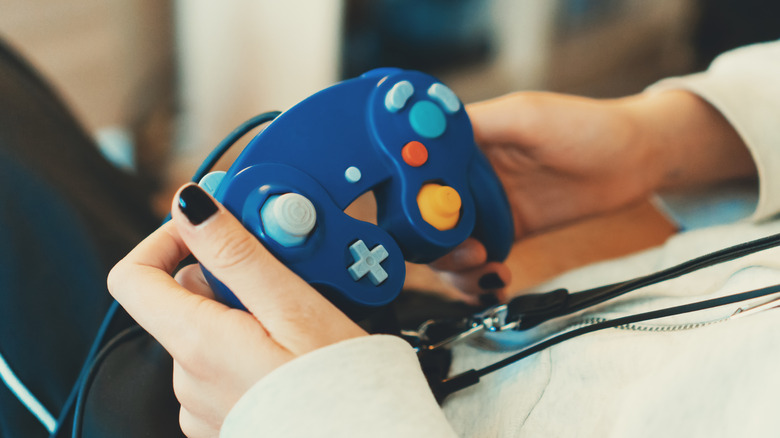 A woman holding a GameCube controller