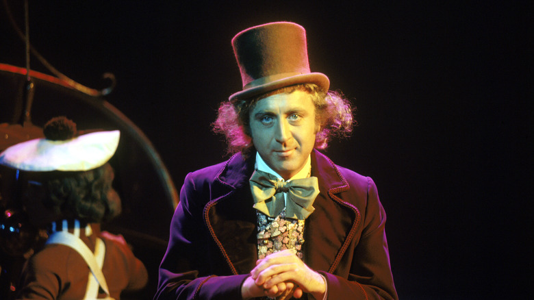 Photo of Gene Wilder on the set of 1971 film Willy Wonka and the Chocolate Factory. He wears a purple tailcoat and a brown top hat.